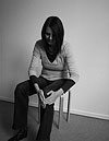 Die Atempädagogin Claudia Kaltenbach sitzt auf einem Hocker und zeigt die Körperübung „Beine hinaufstreichen“.